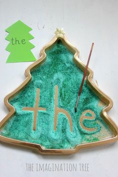 a green christmas tree with the word th e painted on it and an arrow in the center