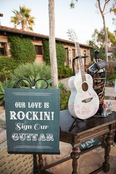 a guitar sitting on top of a table next to a sign that says our love is rockin '