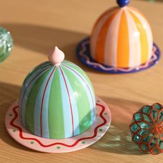 three colorful ceramic objects sitting on top of a wooden table