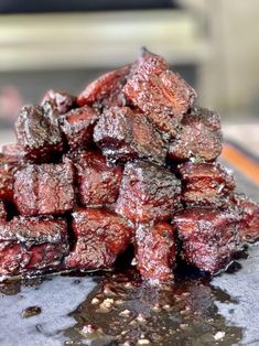 a pile of red meat sitting on top of a metal pan covered in brown stuff