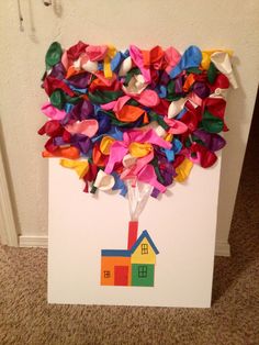 an art project made out of tissue paper with a house on it and colorful streamers in the shape of a tree