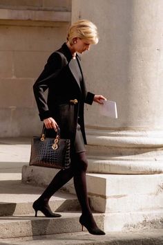 a woman walking down the street carrying a purse