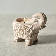 an elephant shaped candle holder with a lit candle in it's trunk on a table