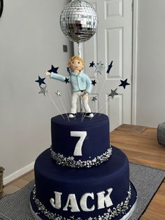 a birthday cake with a boy holding a disco ball and number seven on the top