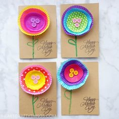 four colorful paper flowers with buttons on them