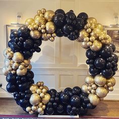 a wreath made out of black and gold balloons