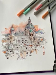 a drawing of a building with two markers on the paper next to it and some pens