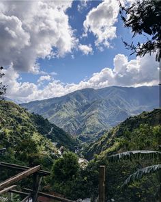 the mountains are covered in green trees and clouds