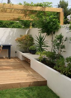 an outdoor patio with wooden flooring and plants on the wall, next to a bench