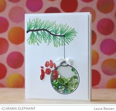 a handmade christmas ornament hanging from a tree branch on a greeting card