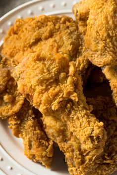 fried chicken on a white plate sitting on a table