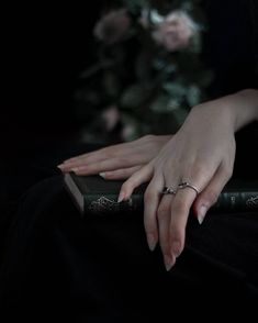 a woman's hands resting on top of a book with flowers in the background