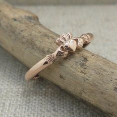 a gold ring sitting on top of a piece of drift wood with two skulls in the middle