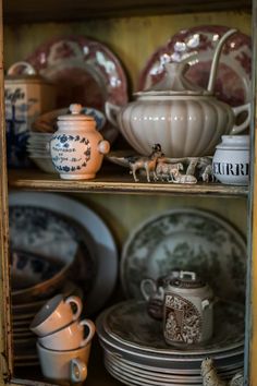 an old china cabinet filled with dishes and other items, including cups and saucers