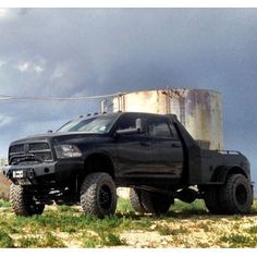 a black truck parked in front of a metal tank on the side of a road