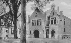 an old black and white photo of a large building with trees in front of it