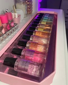 a pink vanity with lots of different types of nail polishes in it and on the counter