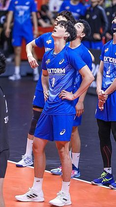 men in blue uniforms standing on a basketball court and looking up at the sky with their eyes closed