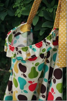 a colorful bag hanging from a tree with polka dots and apples on it's side