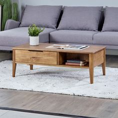 a living room with a couch, coffee table and books on the floor in front of it