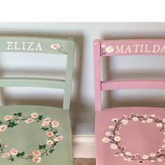 two wooden chairs painted in different colors with flowers on the seat and one has a wreath