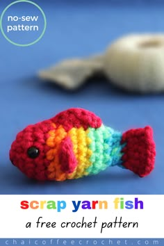 a crocheted rainbow fish sitting on top of a blue surface next to a white object