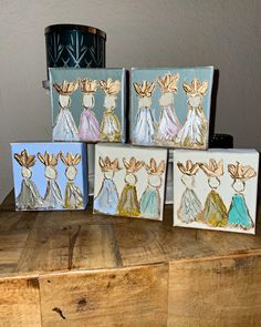 four painted canvass sitting on top of a wooden table