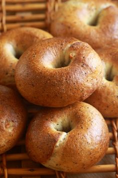 four bagels sitting on top of a wicker basket next to some breadsticks