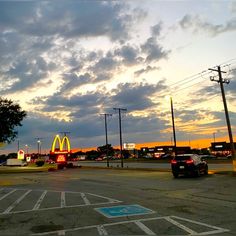 cars are driving down the street in front of a mcdonald's sign at sunset