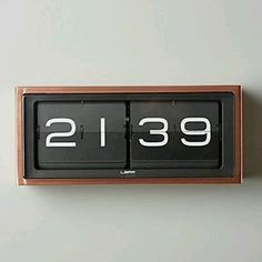 an analog clock with the time displayed on it's display board, in front of a white wall