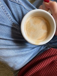 a person holding a cup of coffee in their lap