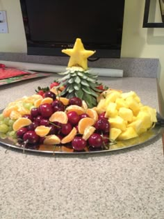 a platter filled with fruit sitting on top of a counter next to a tv