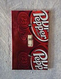 a red light switch plate with two coca cola cans on it