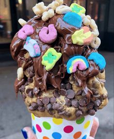 a person holding up a cup filled with ice cream and chocolate covered donut treats