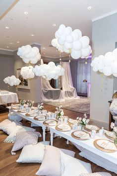 a table set up for a party with white balloons