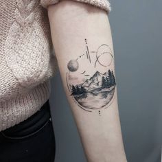 a woman's arm with a tattoo on it that has mountains and trees in the background