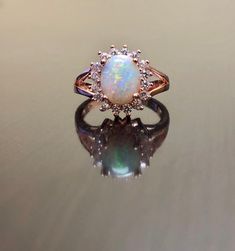 DeKara Designs Collection Our latest design! An elegant and lustrous Opal cabochon surrounded by beautiful diamonds in a halo setting. Metal- 14K Rose Gold, .583. Stones- Center Features an Oval Fiery Australian Opal Cabochon Cut 9 x 7 MM, 17 Round Diamonds, F-G Color VS1 Clarity, 0.32 Carats. Latest of my creations. A beautiful Opal Halo Diamond Ring. The Opal is professionally prong set in between four prongs. There are 17 professionally prong set round diamonds that are surrounding the opal. Luxury 14k Rose Gold Oval Jewelry, Exquisite Rose Gold Rings With Accent Stones, Luxury Rose Gold Cabochon Rings, 14k Rose Gold Oval Center Stone Jewelry, Formal Rose Gold Cabochon Ring, Rose Gold Oval Opal Promise Ring, Elegant Opal Ring With Oval Cabochon And Accent Stones, Elegant Oval Cabochon Opal Ring With Accent Stones, Luxury Rose Gold Halo Jewelry