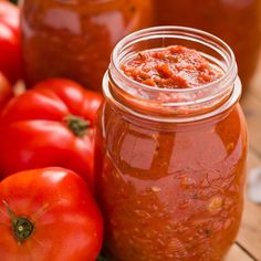 some tomatoes are sitting next to a jar of tomato sauce