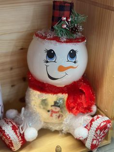 a snowman sitting on top of a wooden shelf