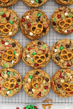 cookies decorated with pretzels, m & m and candy are on a cooling rack