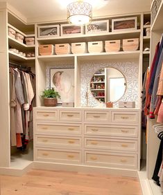 an organized closet with white drawers and lots of clothes hanging on the shelves, along with baskets