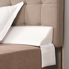 a close up of a bed with pillows and sheets on top of the headboard