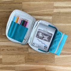 an open pencil case sitting on top of a wooden floor