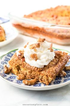 a piece of cake on a plate with whipped cream and pecans in the background