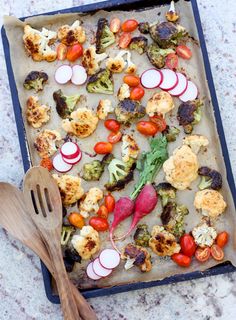 a tray filled with different types of veggies on top of a table next to a wooden spatula