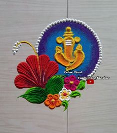 an embroidered badge with flowers and leaves on the side of a wooden surface, depicting ganeshi