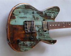 an electric guitar is painted green and brown with rusted parts on the top, bottom and sides