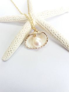 Beautiful gold sea shell necklace made with a gold plated seashell charm with a gold filled chain and fresh water pearl. This necklace makes a unique gift for a beach lover or someone special in your life. The seashell is around 15- 20mm long. Each item is carefully packaged in a beautiful jewellery box ready as a gift. If you would like to add a personalized note with your order, just write a note at checkout and I will send a small card with your gift to the recipient. Please choose necklace l Elegant Beach Charm Necklaces With Pearl, Elegant Shell-shaped Charm Necklaces For Beach, Gold Shell Necklace With Pearl Pendant For Beach, Elegant Pearl Charm Necklaces For Beach, Gold Pearl Chain Necklace For Beach, Gold Pearl Chain Jewelry For Vacation, Beach Shell Pendant Necklace With Pearl Charm, Beach Shell-shaped Charm Necklaces With Pearl, Beach Jewelry With Pearl Pendant In Shell Shape