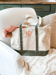 a tote bag sitting on top of a white chair next to pillows and blankets