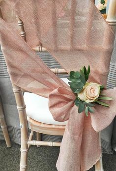 a chair with a flower on it sitting in front of a curtain and some chairs